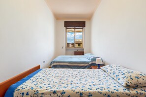 Un dormitorio con dos camas, una ventana, una mesita de noche y una pequeña mesa.