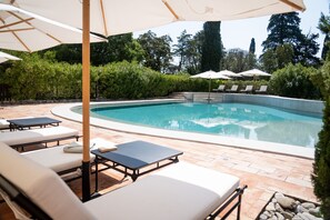 Una piscina al aire libre, sillones reclinables de piscina