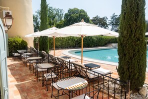 Un área junto a la piscina con mobiliario exterior y sombrillas.