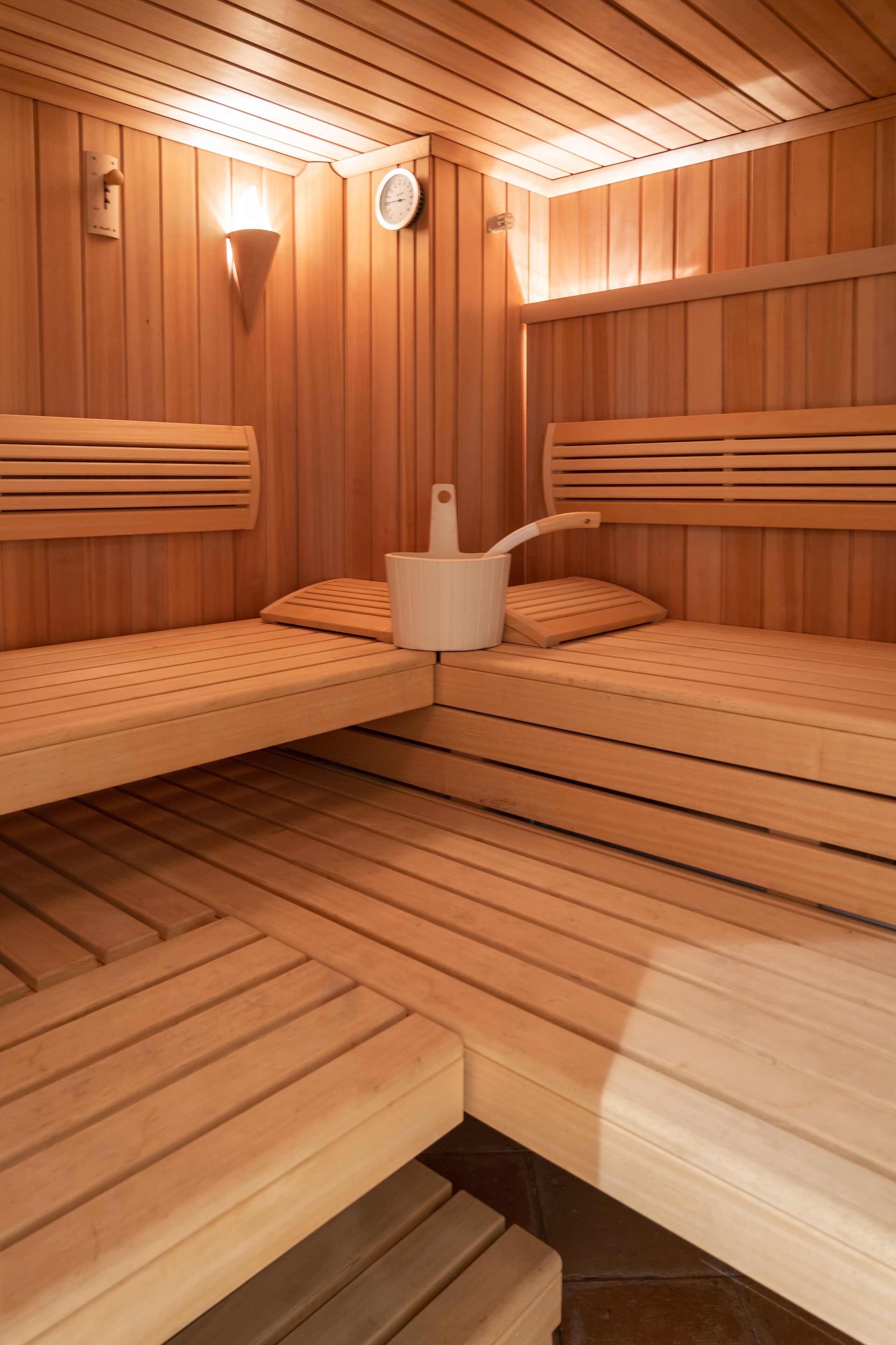 A sauna with wooden benches and a central heater.