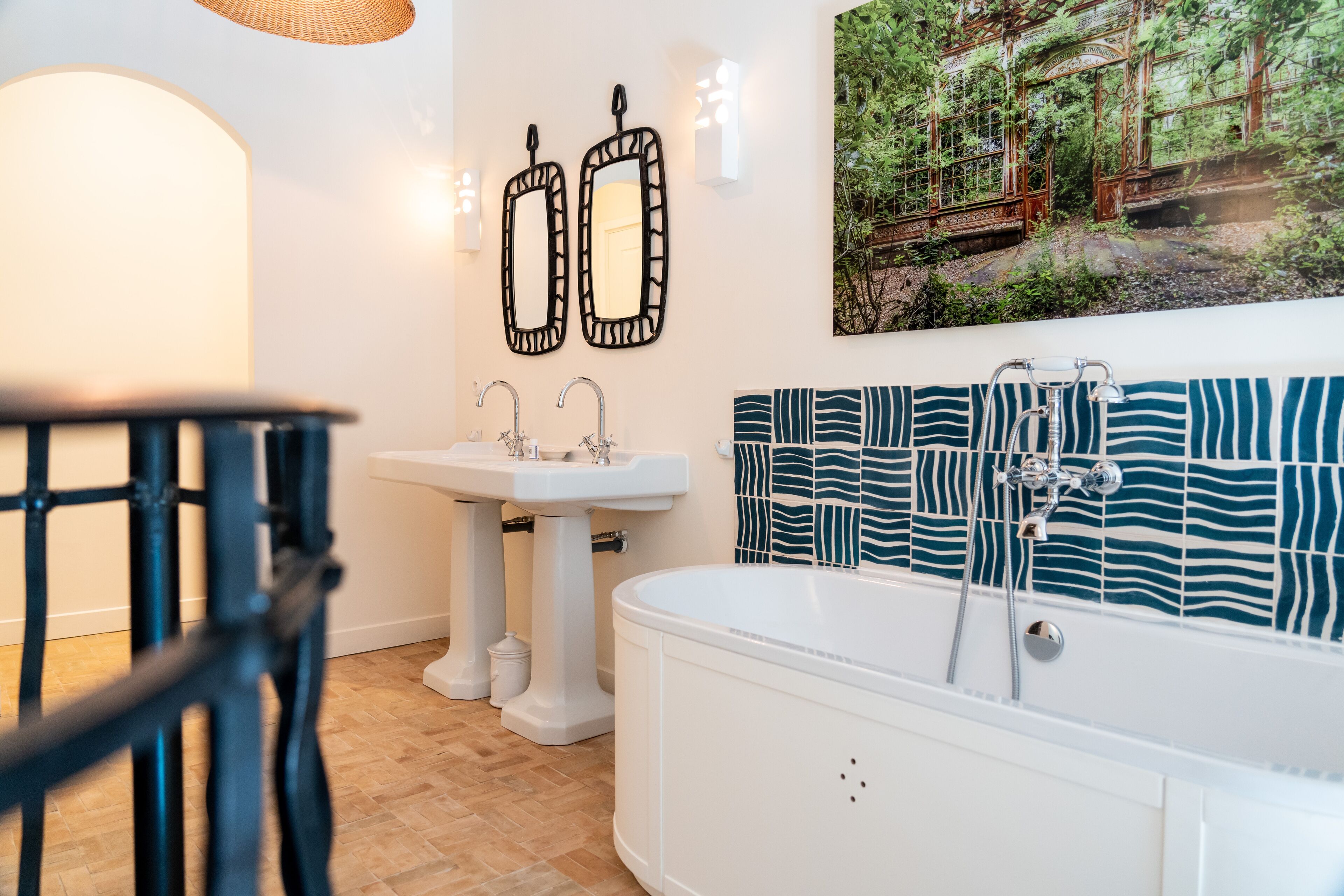 A bathroom with a white bathtub, two sinks, and a large mirror.