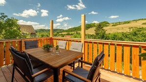 A wooden deck with a table and chairs, overlooking a green landscape. - Rustic Eifel - Garden, kitchen - Hiking, bike trails & self-check-in (Gerolstein)