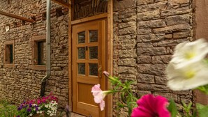 A stone building with a wooden door and windows, surrounded by potted flowers. - Rustic Eifel - Garden, kitchen - Hiking, bike trails & self-check-in (Gerolstein)