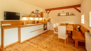 A modern kitchen with wooden countertops, a built-in oven, and a dining area with a bench and chairs. - Rustic Eifel - Garden, kitchen - Hiking, bike trails & self-check-in (Gerolstein)