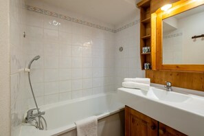 Bathroom features a large bathtub, separate sink area, and a wooden cabinet with a mirror.