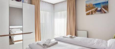 A modern hotel room with a bed, a wardrobe, and a painting on the wall.