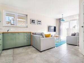 Relax in this spacious living area with a comfortable sofa, flat-screen TV, and adjacent kitchen.