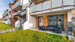 Een modern appartementencomplex met balkons, een overdekt terras en een verzorgd gazon.