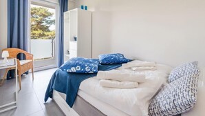 Een slaapkamer met een bed, een stoel, een garderobe en uitzicht op het omliggende landschap.