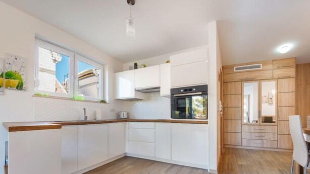 Een moderne keuken met witte kasten, een houten aanrechtblad en een ingebouwde oven.