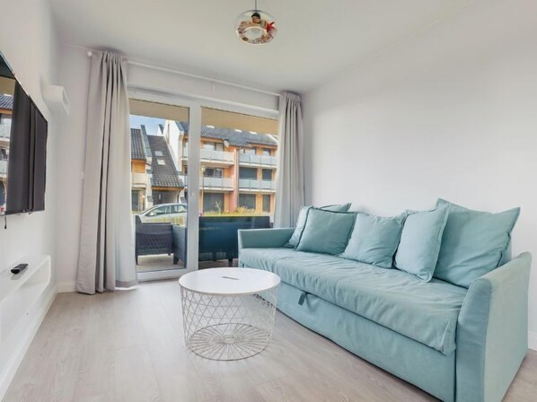 Relax in this stylish living room with a sofa, coffee table, and flat-screen TV, plus a balcony with city views.