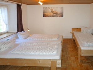 A room with two wooden beds, a window with curtains, a wall-mounted picture of a deer, and a wooden floor. - Hexenstüble by Interhome (Simonswald)