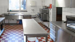 Eine Küche mit Schachbrettboden, Edelstahlgeräten, einem großen Tisch und einem Fenster.