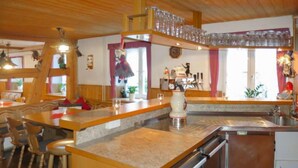 Eine Küche mit einer zentralen Kochinsel, Barhocker, einem Kühlschrank und einer Spüle.