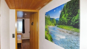 Ein Flur mit Holzboden und einem Gemälde von einem Fluss und Wald an der Wand.