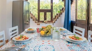 Una mesa de comedor con platos de pasta, una jarra de agua y un frutero.