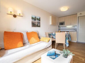 A compact living space with a sofa, a dining area, and a kitchenette.