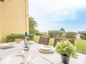 An outdoor dining area with a table set for two, a bottle of water, and a potted plant.