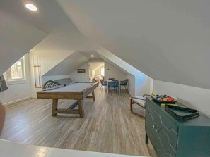 Une pièce de style loft dotée d’une table de billard, d’un porte-tailles et d’un coin repas avec des chaises.