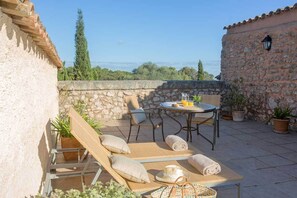 An outdoor patio with a table, chairs, and lounge chairs. - Agroturismo Son Cardaix (Arta)