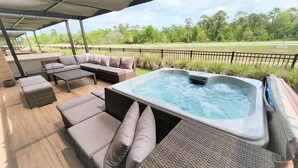 Un espace extérieur aménagé avec des meubles en osier, un jacuzzi et une vue sur un terrain de golf.
