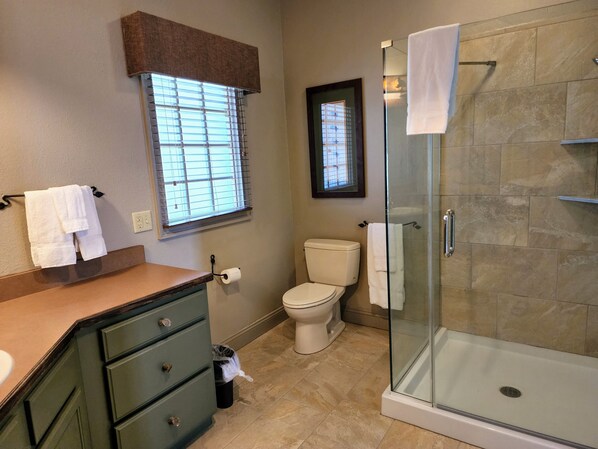 A bathroom with a glass shower enclosure, a toilet, a sink with a vanity, and a window with blinds. - 1 Bedroom Lodge, WILDERNESS CLUB AT BIG CEDAR Ridgedale, MO (Ridgedale)