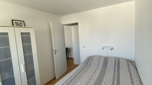Un dormitorio con cama, armario y puerta que da a otra habitación.