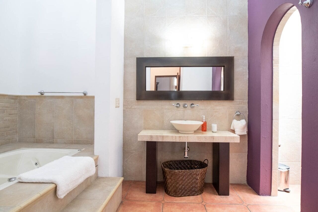 Un baño con bañera, un lavabo con espejo y un perchero para toallas.