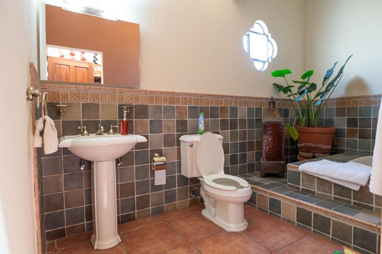 A bathroom with a pedestal sink, toilet, and a mirror above the sink.