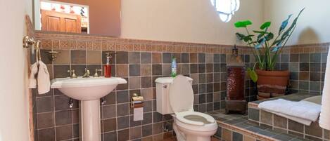 A bathroom with a pedestal sink, toilet, and a mirror above the sink.