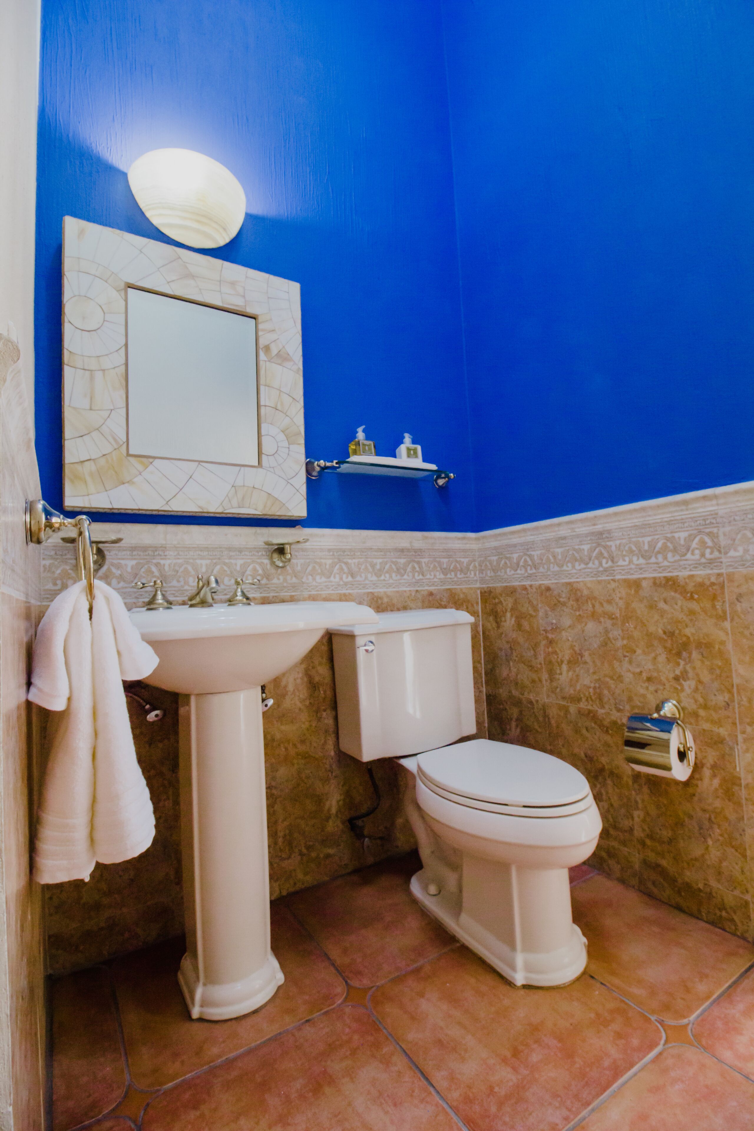 Un baño con lavamanos blanco, inodoro y paredes azules.