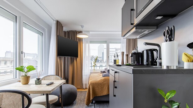 A modern kitchen with a dining area, large windows, and a flat-screen TV. - Limehome Essen Kettwiger Str. (Essen)