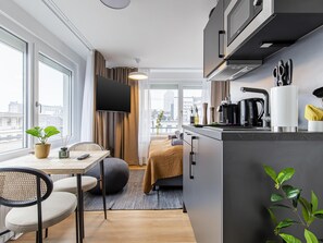 A modern kitchen with a dining area, large windows, and a flat-screen TV. - Limehome Essen Kettwiger Str. (Essen)