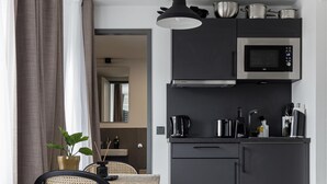 A compact kitchen with modern appliances, a dining area with a table and chairs, and a cozy seating area with a rug. - Limehome Essen Kettwiger Str. (Essen)