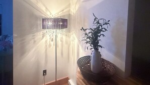 Une pièce avec un lampadaire, une plante en pot et un plancher en bois.