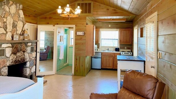 A cozy cabin interior with a stone fireplace, a dining area, and a kitchen.