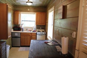 A compact kitchen with wooden cabinets, a microwave, a sink, a stove, and a trash can. - Cabin 2 on beautiful Grand lake! Great for fishing, swimming and boating.  (Dennis)