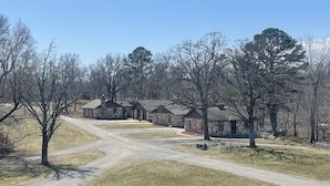 A row of stone cabins with a dirt path leading to them, surrounded by trees and open grassy areas.