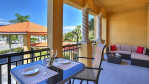 A balcony with a dining table, chairs, and a sofa.