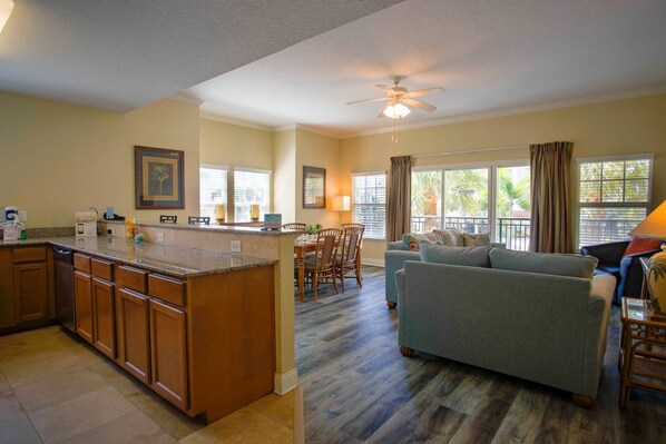 A spacious living area with a kitchen, dining table, and a large window providing a view of the outdoors.
