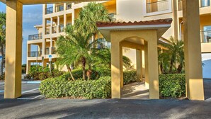 A covered outdoor area with a palm tree and a building with multiple balconies. - Two Private Balconies! Heated Waterfront Pool & Hot Tub, Fish From the Dock, Just Steps to the Beach (Treasure Island)