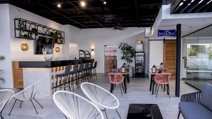 Eine moderne Bar mit weißen Stühlen, einer Theke und einem Schild für 'Caffè Borbone'.