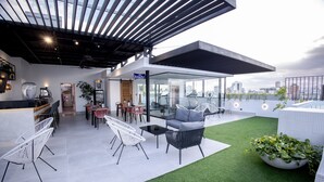 Eine Dachterrasse mit Außenmöbeln, einer Glaskuppel und Blick auf die Stadtlandschaft.