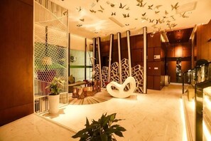 A modern hotel lobby with a marble floor, a large white abstract sculpture, and a glass partition with a geometric pattern. - Ceeci Hotel (Xichuan)