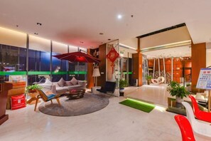 Un moderno vestíbulo de hotel con una zona de estar, una recepción y un amplio ventanal con vistas a la ciudad.