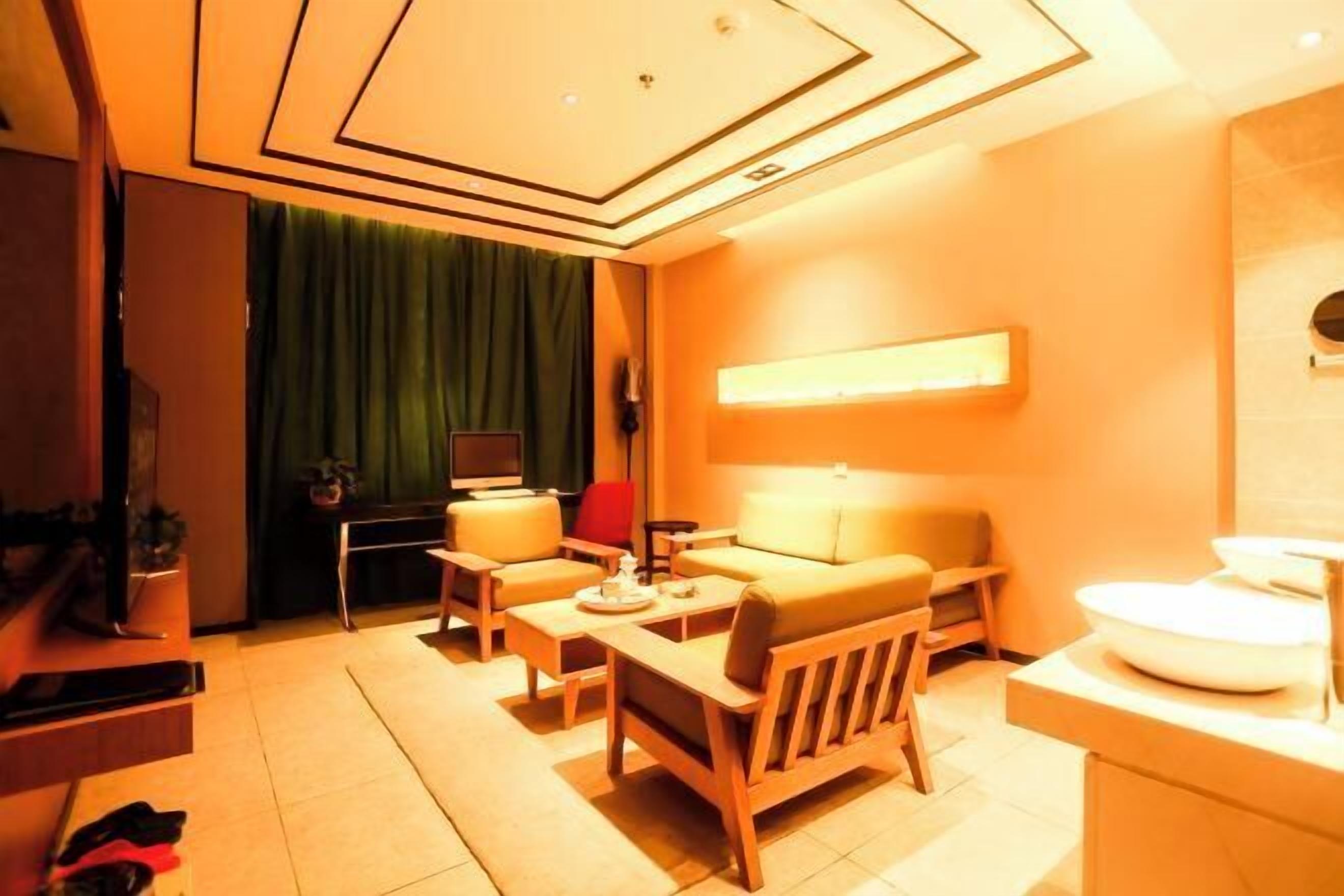 A modern living room with a sofa, armchairs, a coffee table, and a TV.