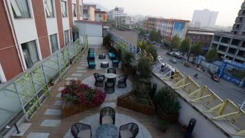 Una terraza en la azotea con mobiliario exterior, vistas de la ciudad y una calle abajo.