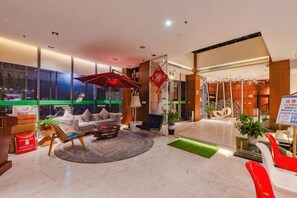 A modern hotel lobby with a seating area, a reception desk, and a large window offering a view of the cityscape. - Ceeci Hotel (Xichuan)