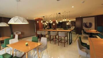 A modern restaurant interior with a bar area, seating arrangements, and pendant lighting.