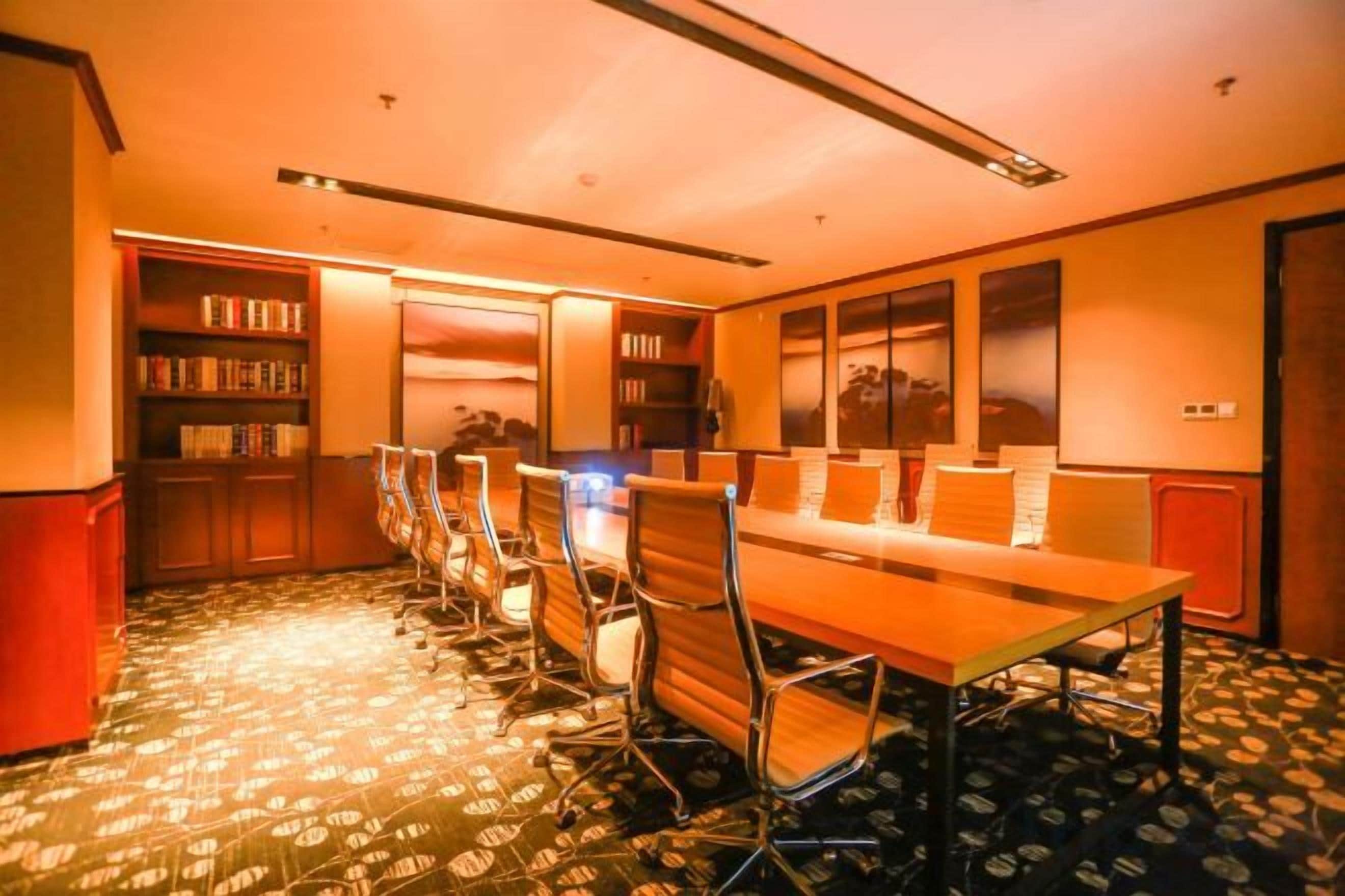 A conference room with a long table, chairs, and bookshelves.